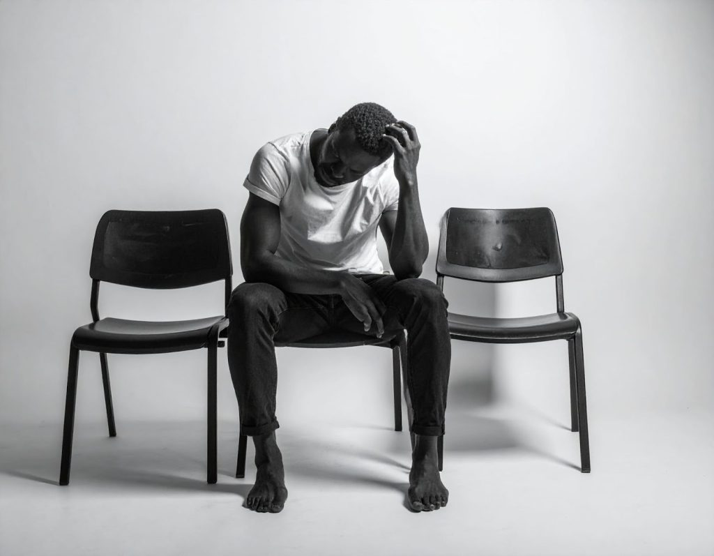 男性坐在椅子上，身體不適