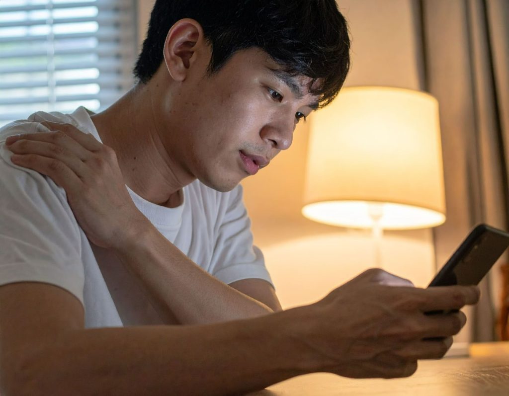 久坐滑手機的年輕人，僵硬揉著肩膀