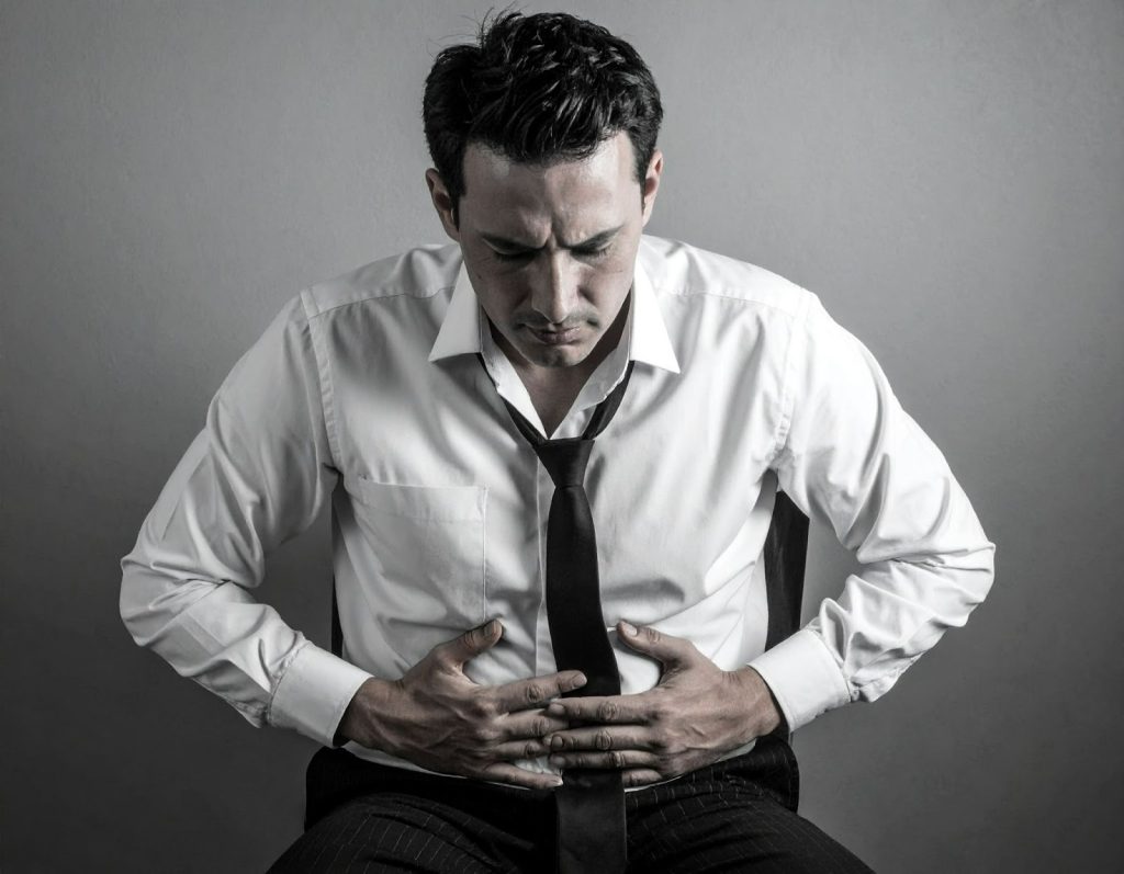 男性坐在椅子上表情不適，感覺下腹疼痛