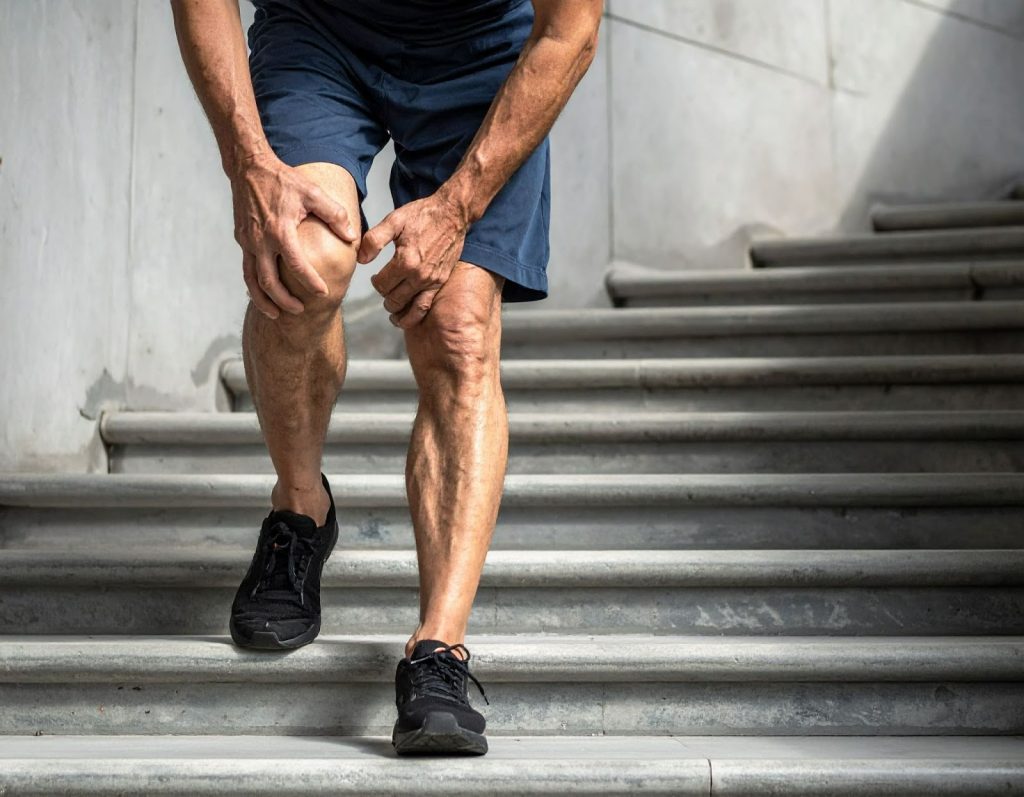 中年男性走樓梯時扶著膝蓋,表情不舒服 中年男性走樓梯時扶著膝蓋,表情不舒服