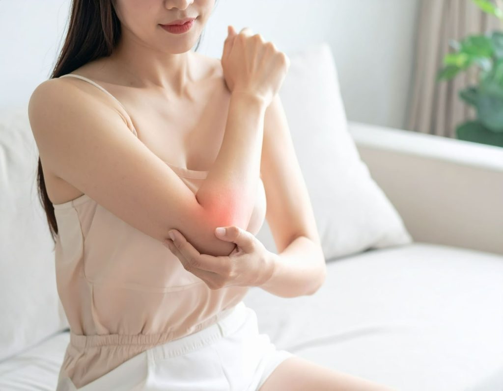 女性在沙發上按摩手肘疼痛的地方