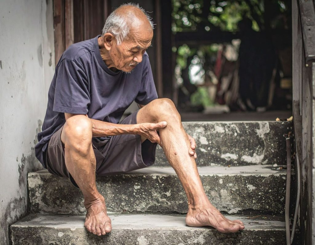 一名老人下樓梯的時候扶著膝蓋,表情不適 一名老人下樓梯的時候扶著膝蓋,表情不適