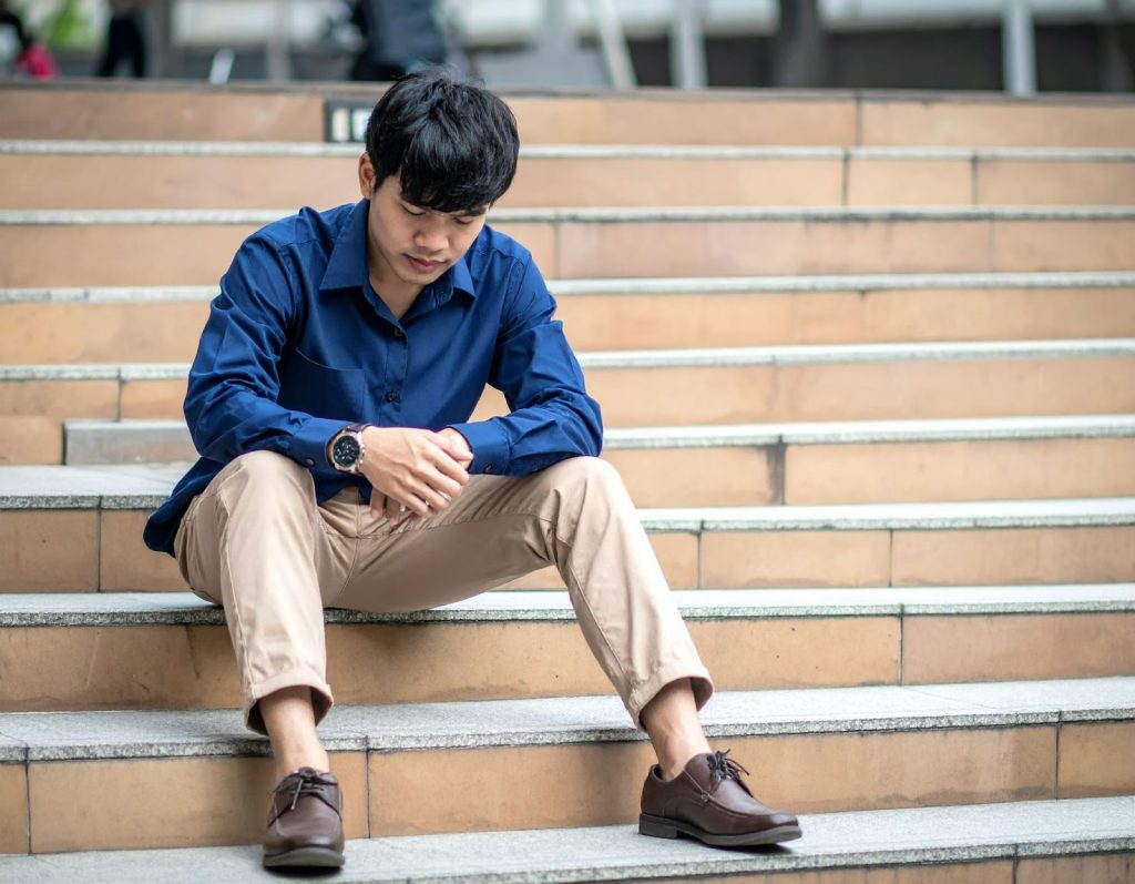 男性坐在樓梯上扶著膝蓋感到不適